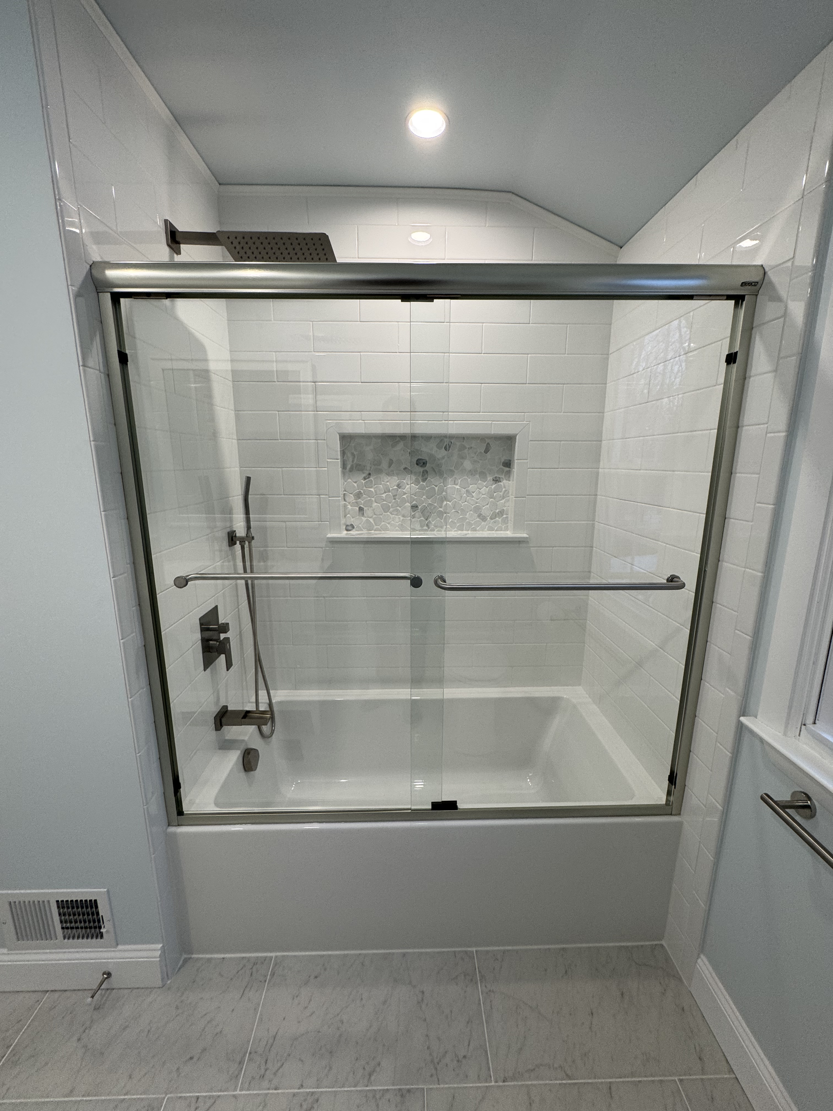 Luxury frameless glass shower enclosure with white subway tile and marble accent