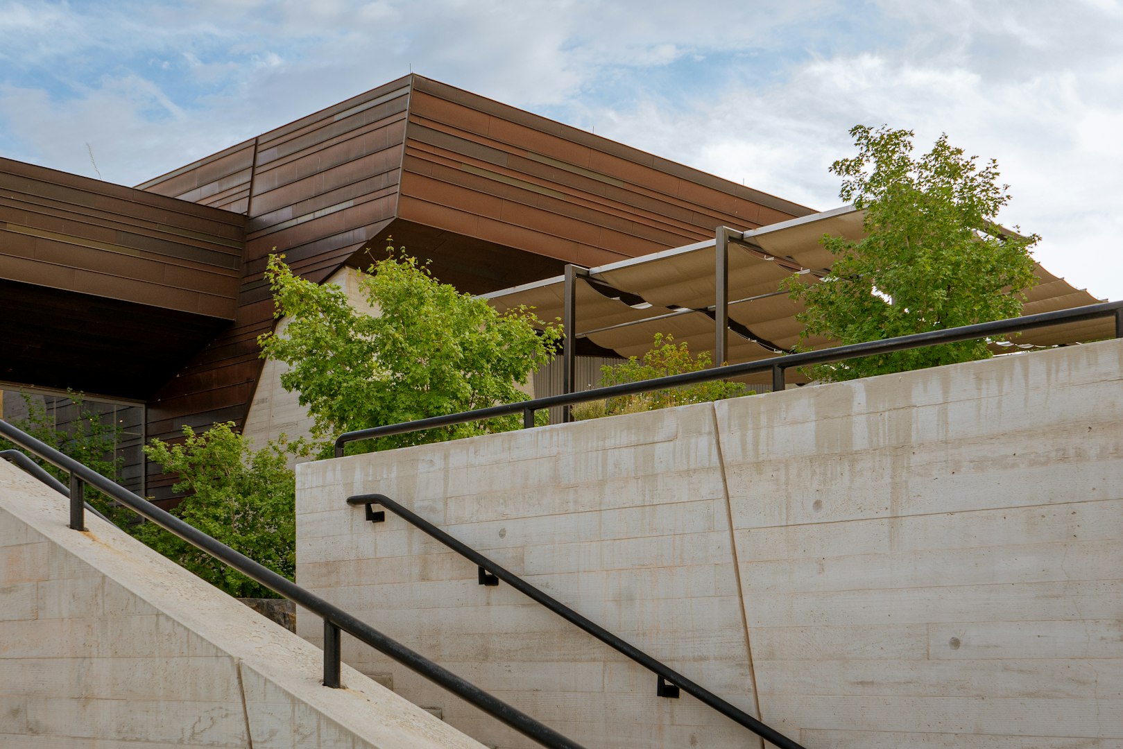 A modern commercial building exterior featuring clean concrete masonry walls, metal railings, and landscaped greenery — highlighting quality commercial masonry construction.