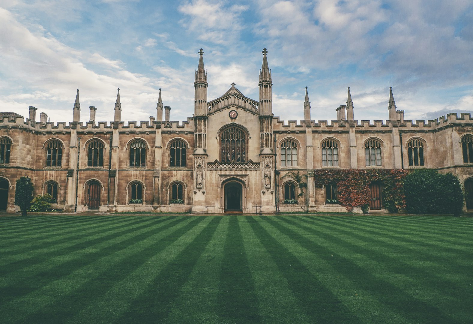 A historic classical stone building with arched windows, tall spires, and a well-manicured lawn in front, representing the preservation and modern restoration of grand architectural landmarks.