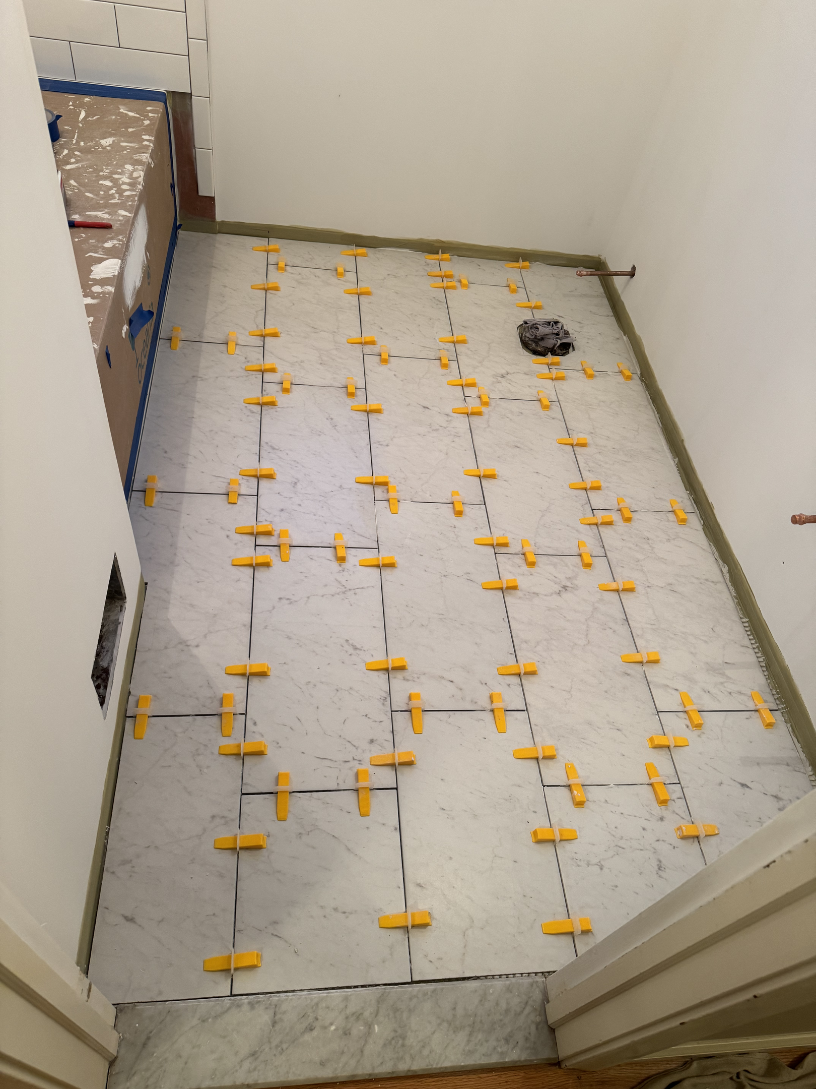 Bathroom floor tile layout with orange marking grid for precise installation planning