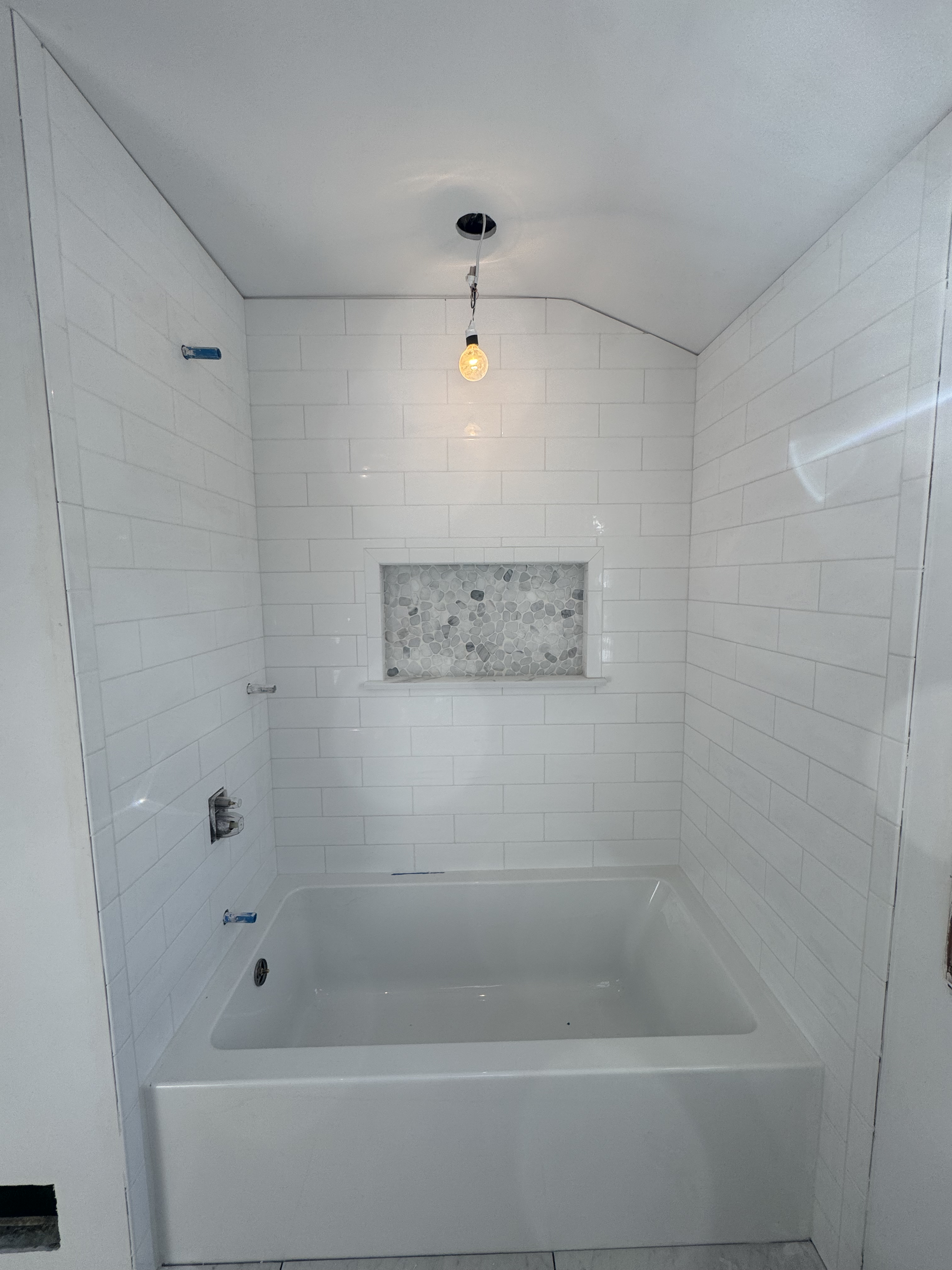 Finished bathroom shower with white subway tile walls and marble mosaic accent