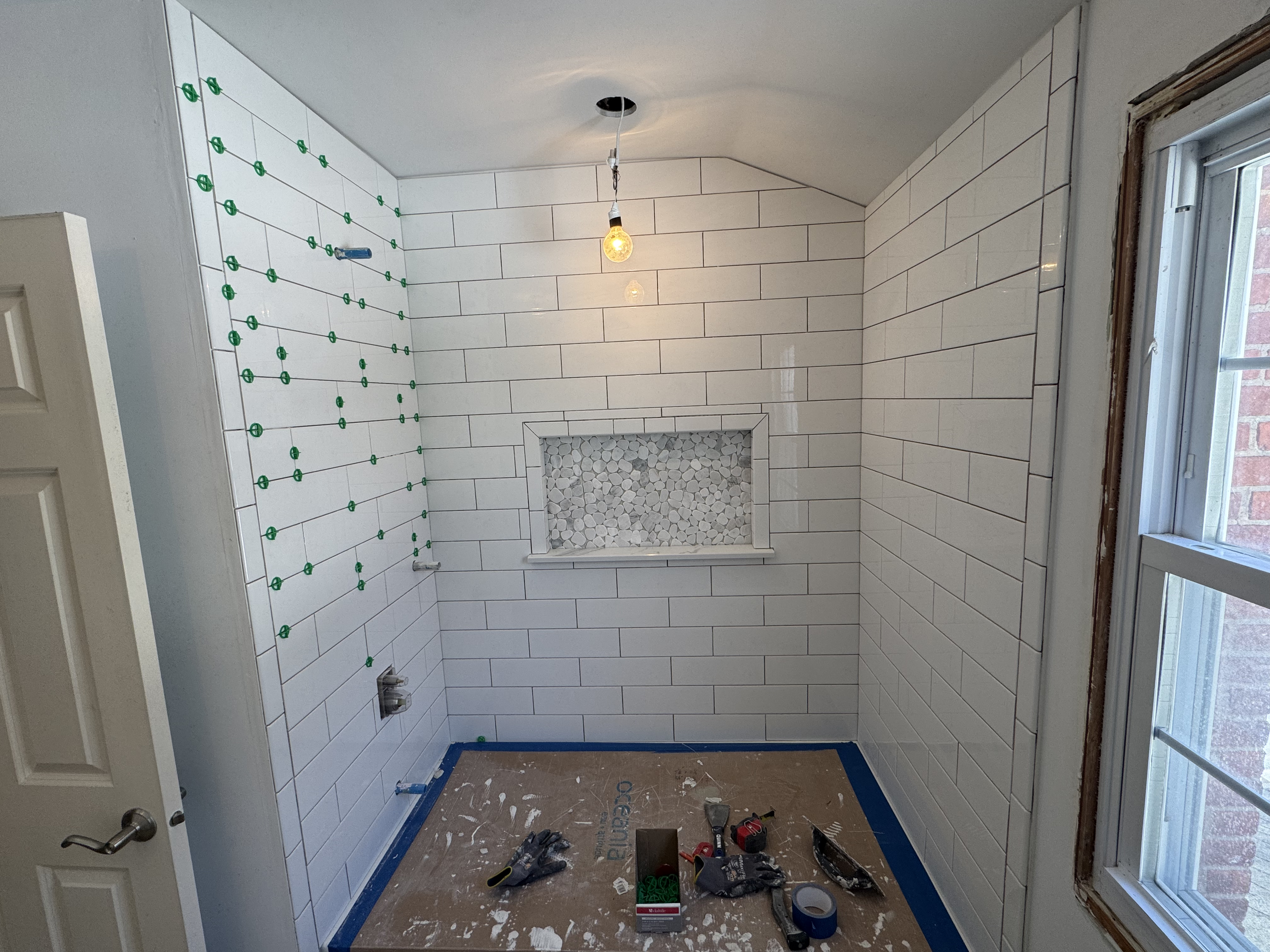 White subway tile shower with decorative accent tile and lighting