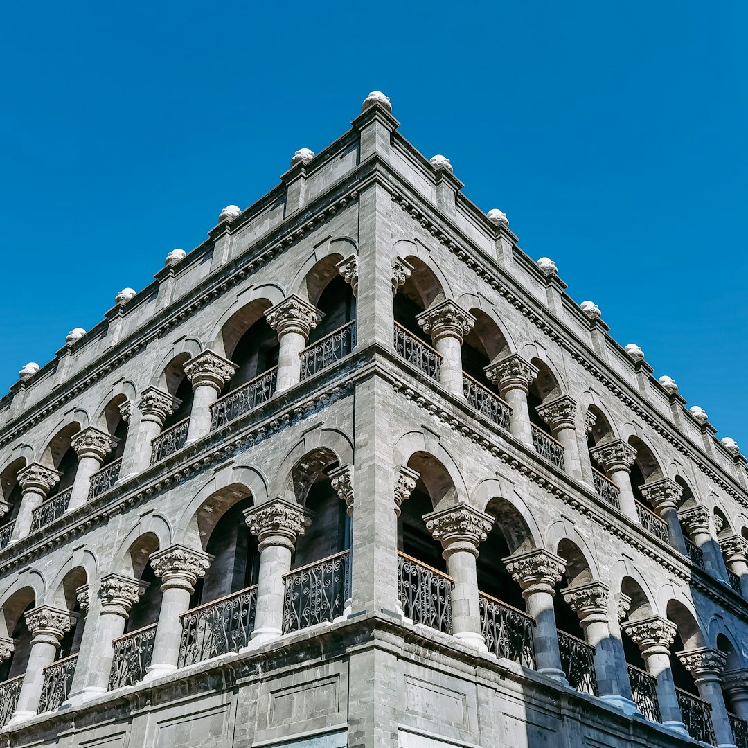 A historic stone building facade with arched windows and detailed columns, showcasing expert structural restoration and masonry preservation work.